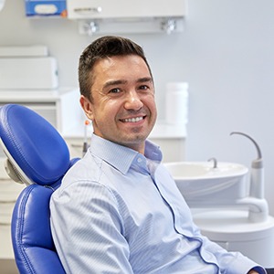 Man in button-up shirt sitting in dental chair and smiling
