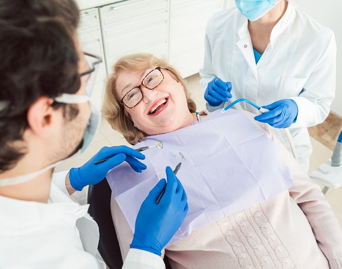Adult woman in treatment chair smiling at dentist