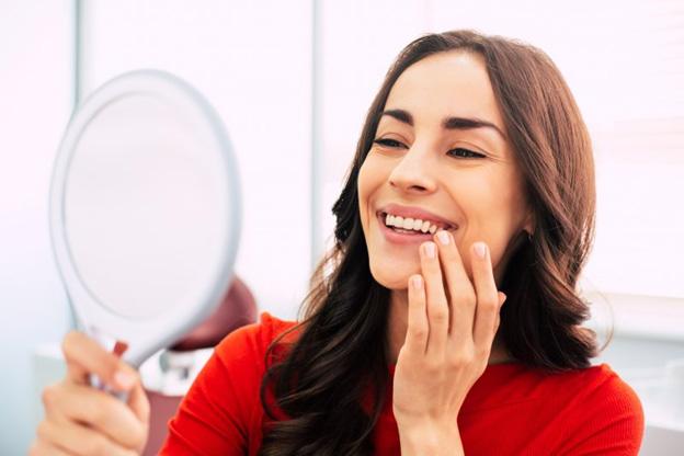 Woman looking at her smile in a small mirror