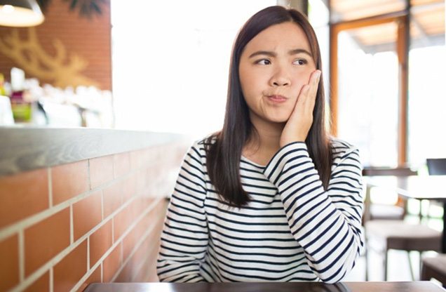 Woman holding her jaw at a restaurant