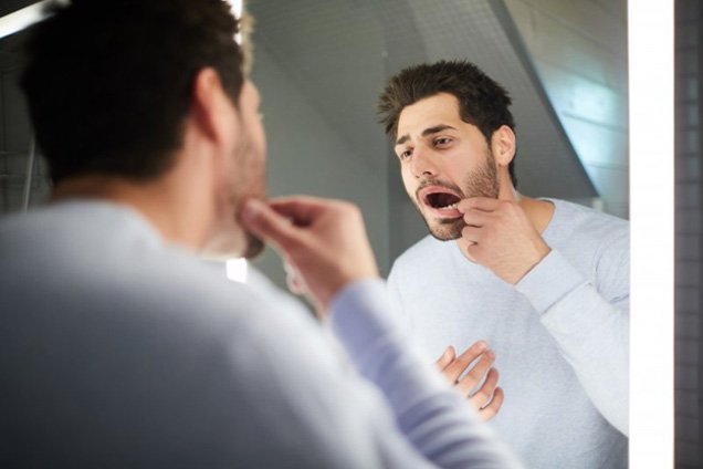 Man checking on his gums in mirror
