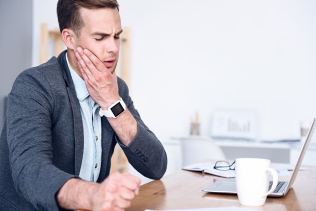 Man rubbing his jaw at his desk