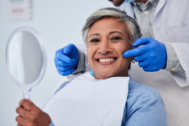 Woman looking at her smile in a small mirror