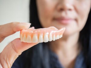 Dentist holding denture in foreground.