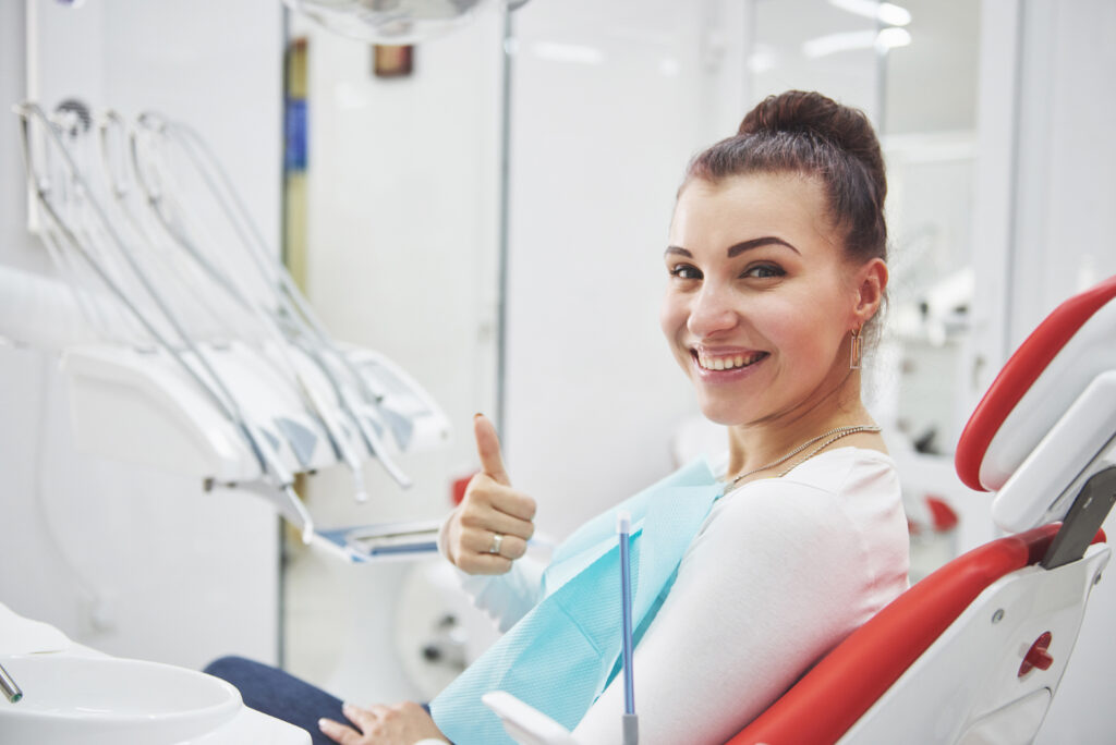 Satisfied patient showing her perfect smile after treatment in a dentist clinic.