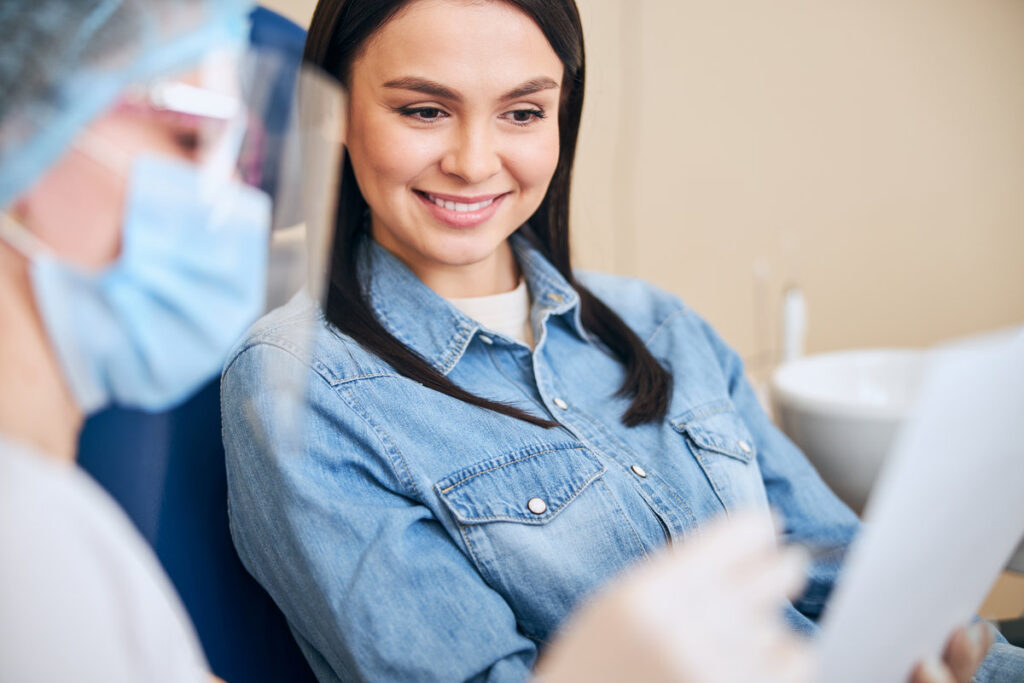 Cheerful brunette keeping smile on her face while being glad of teeth whitening procedure