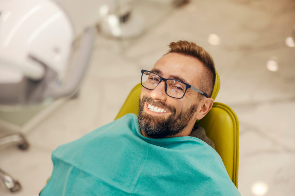 Portrait of a patient at dentist office sitting in the chair while smiling at the camera with perfect smile.