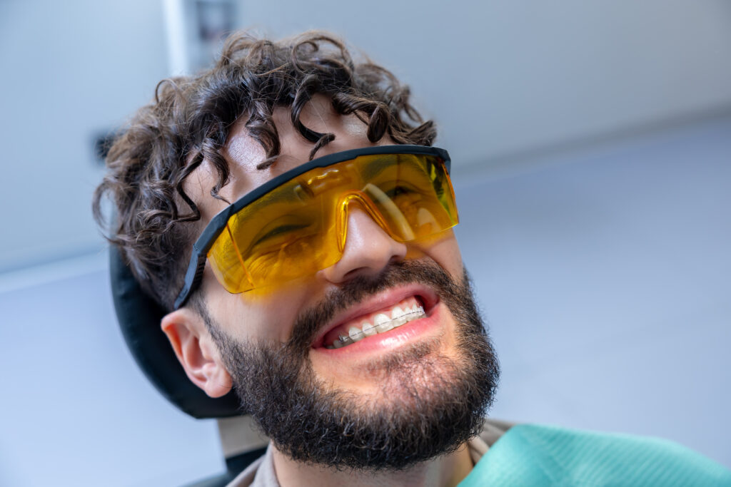 Caucasian man patient during whitening teeth procedures in modern dental clinic