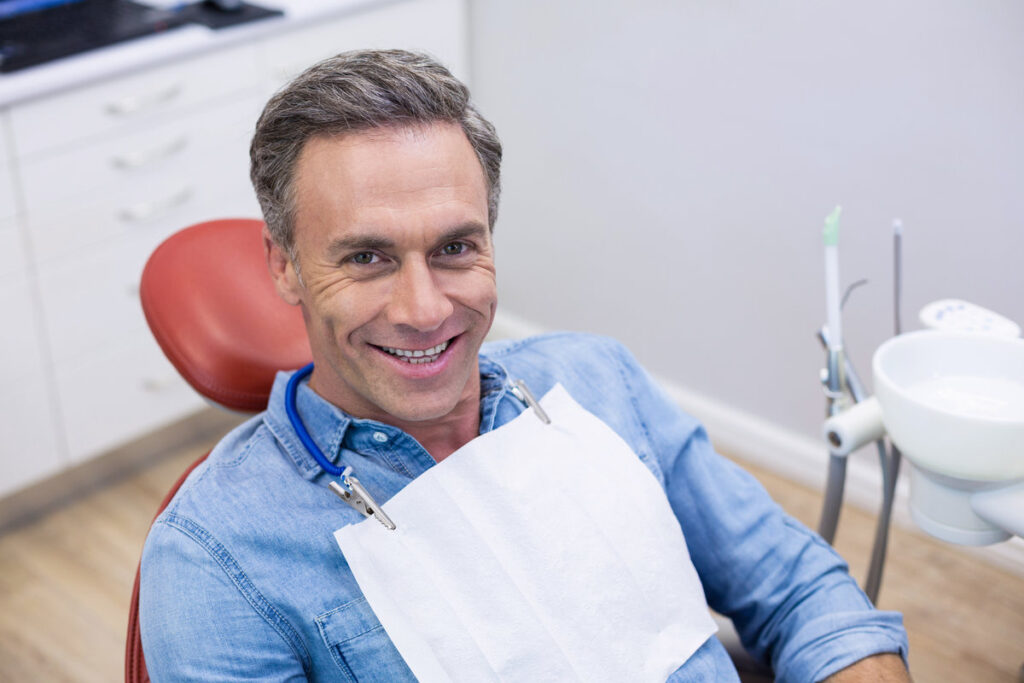 Smiling patient sitting on dentist chair