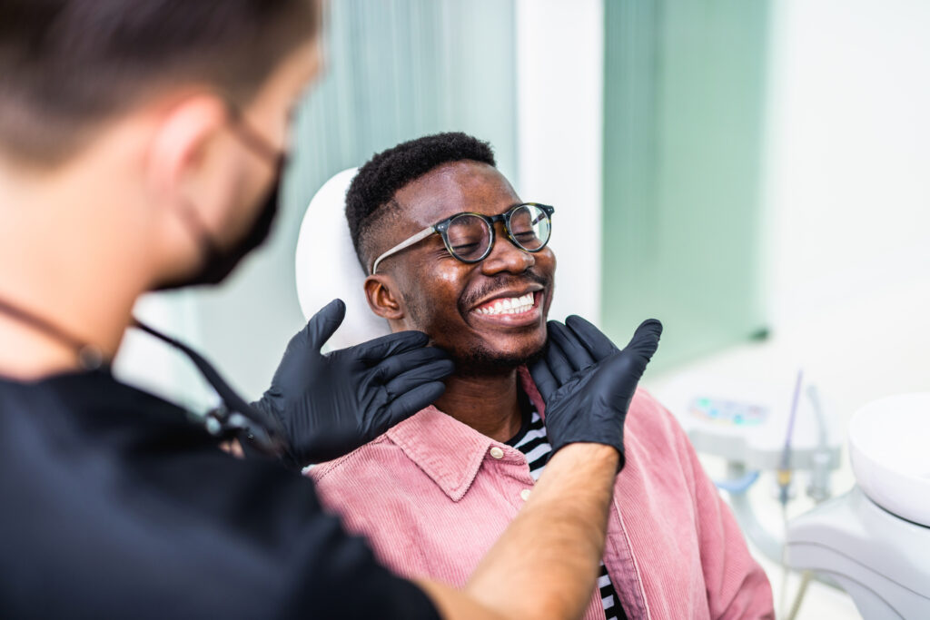 African American young man having a visit at the dentist's. He is sitting on chair at dentist office in dental clinic.