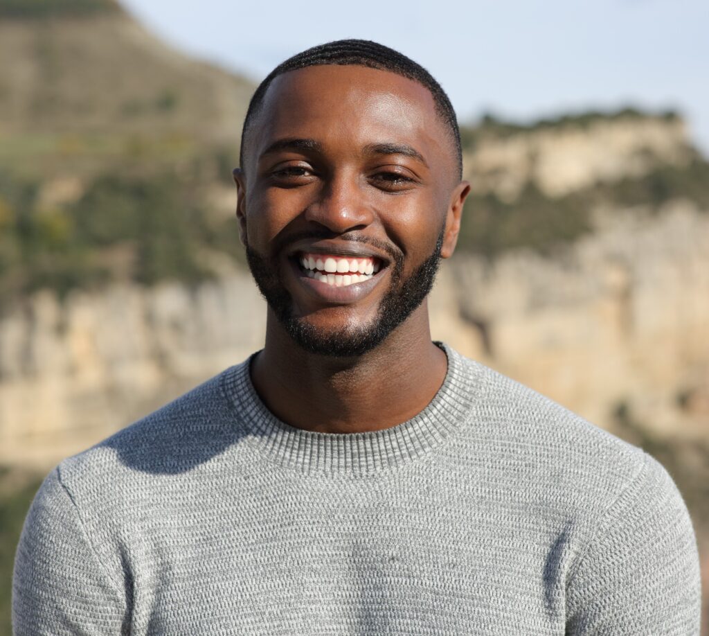 Happy man with black skin smiling at camera in the mountain
