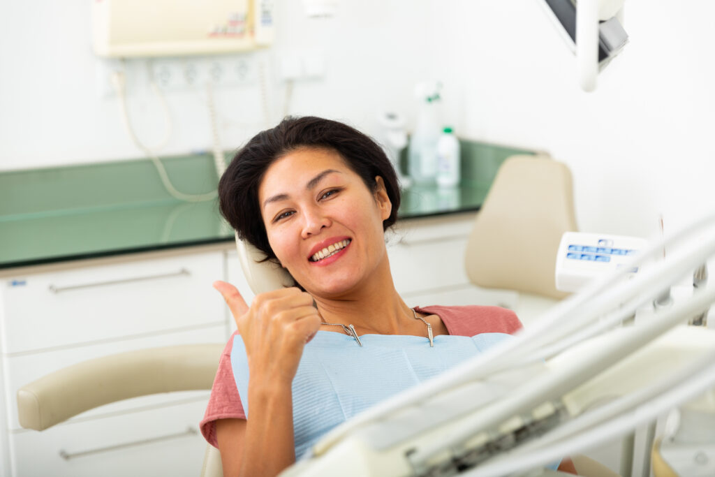 Portrait of a satisfied asian woman patient sitting in a dental chair in the clinic office