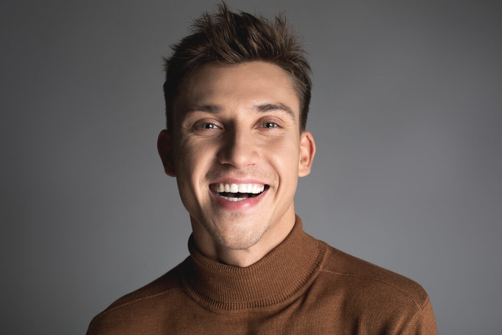 Happiness concept. Portrait of cheerful male person with snow white teeth and disheveled short hair. Isolated on background