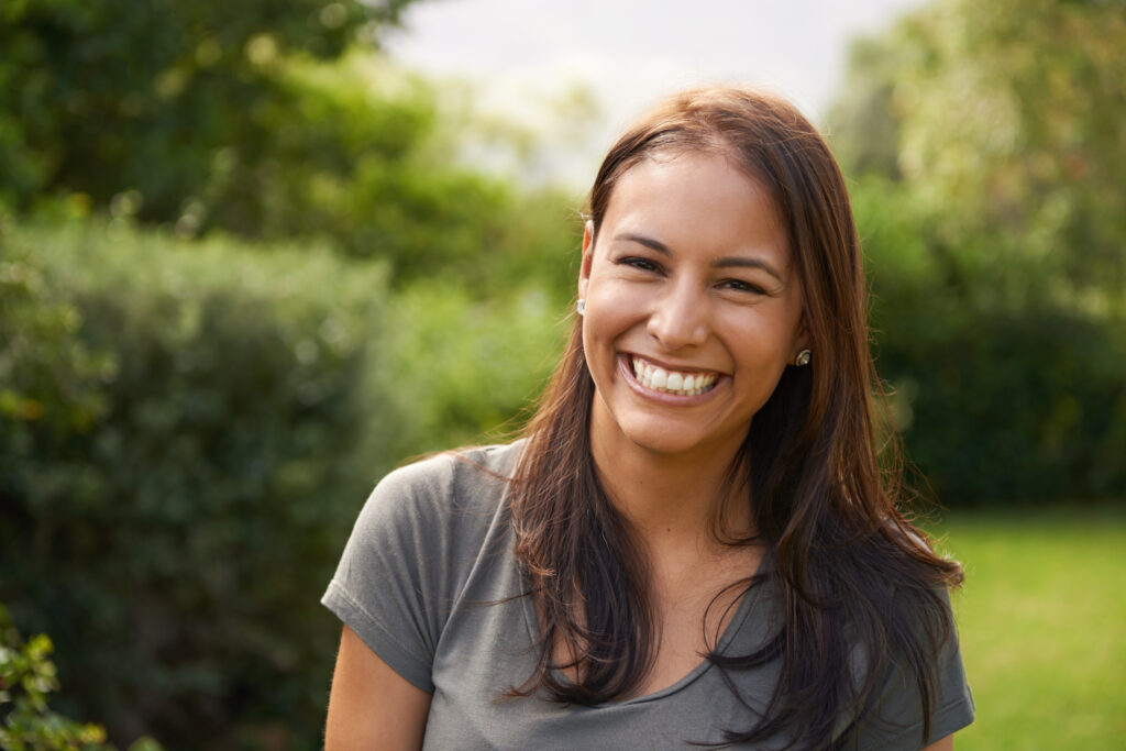 A beautiful young woman smiling outdoors.