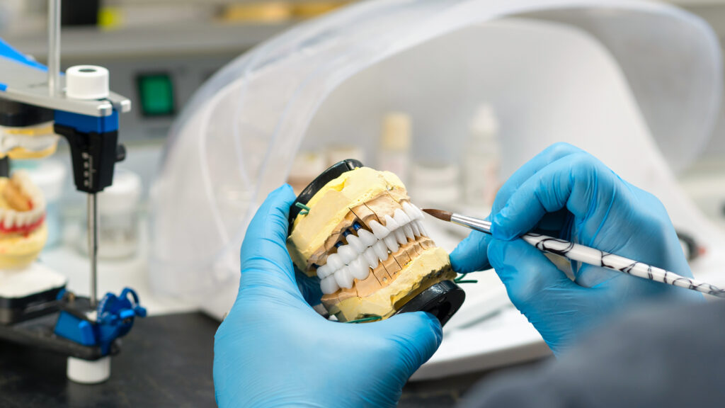Dental prosthesis work. Denture work. Teeth painting. Dental technician working with tooth denture at prosthesis laboratory