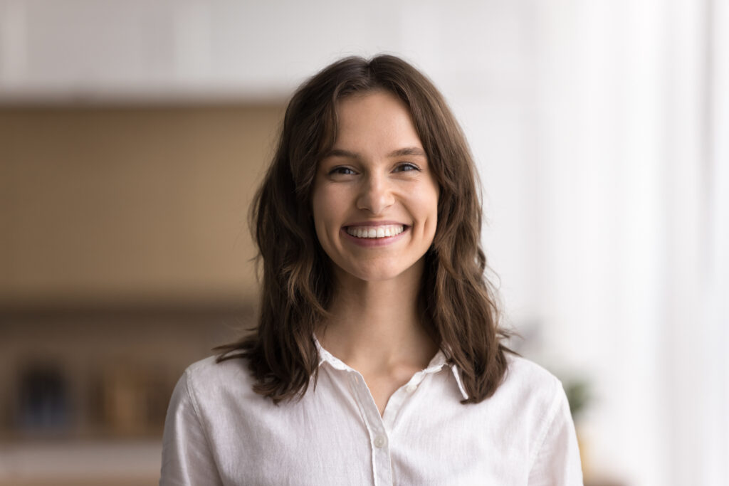 Positive lifestyle portrait. Headshot beautiful young adult woman with long dark wavy hair successful entrepreneur university student satisfied client looking at camera with bright healthy white smile