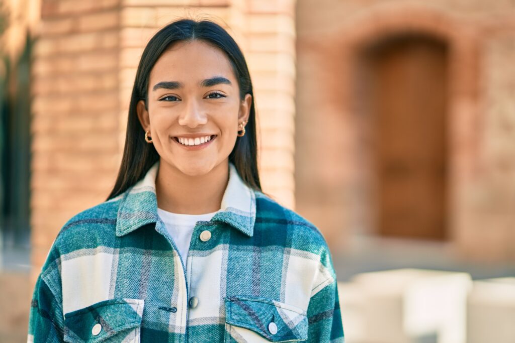 Young latin girl smiling happy standing at the city.