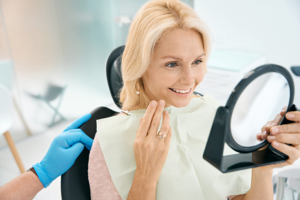Close up portrait of pretty Caucasian female enjoying her beautiful smile after the dentistry treatment in medicine center