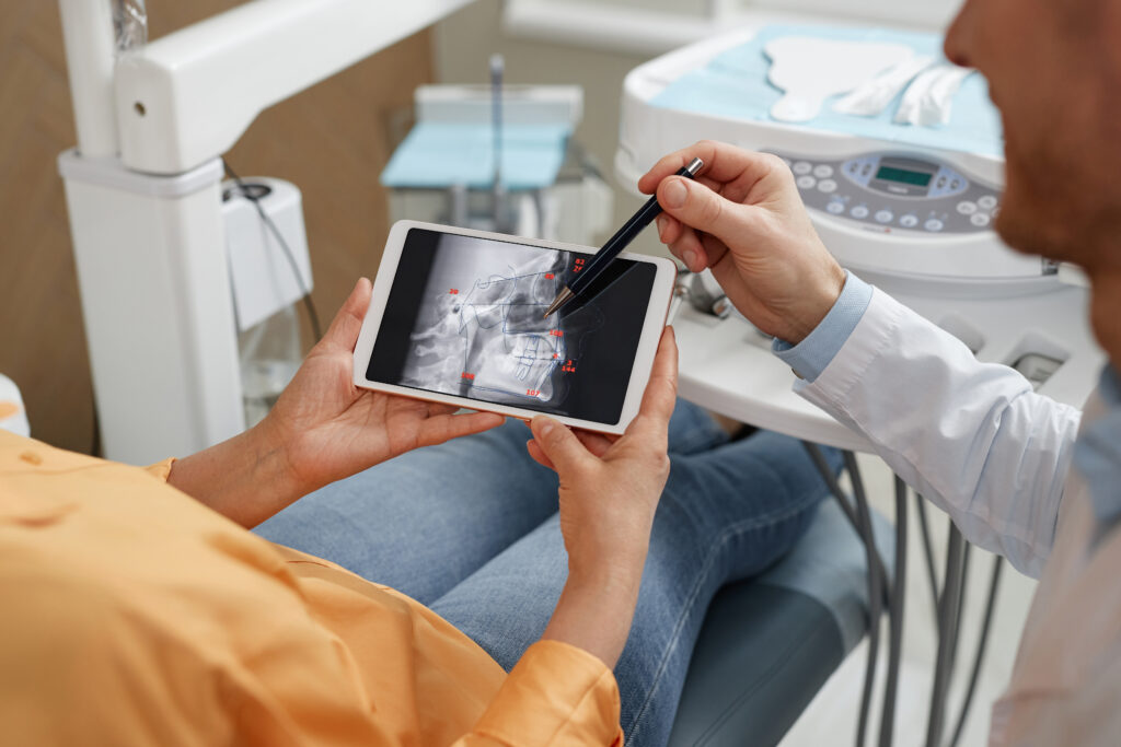 Dentist reviewing a dental X-ray on a tablet with a patient during consultation