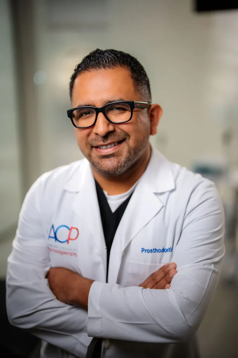 Dr. Eugenio Aquino, prosthodontist in Naples, FL, smiling in a white coat